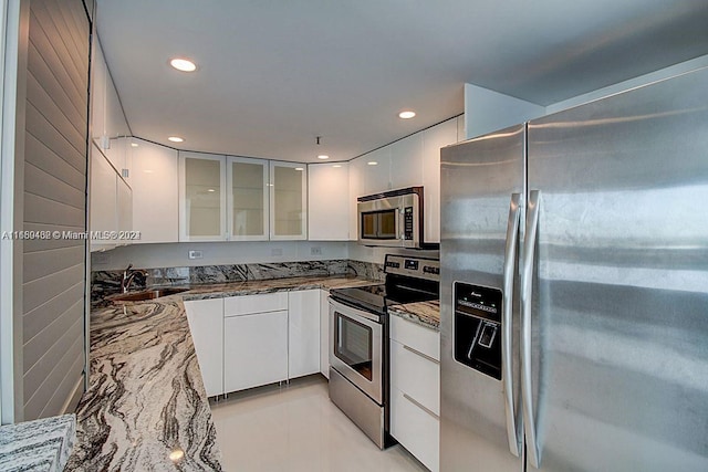 kitchen with dark stone countertops, appliances with stainless steel finishes, sink, and white cabinets