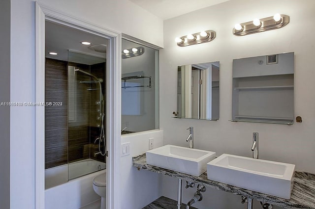 full bathroom featuring toilet, sink, and shower / bath combination with glass door