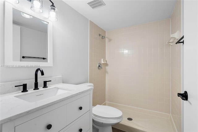 bathroom with vanity, toilet, and tiled shower