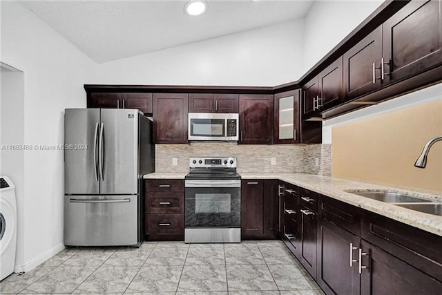 kitchen featuring sink, vaulted ceiling, washer / dryer, dark brown cabinets, and appliances with stainless steel finishes