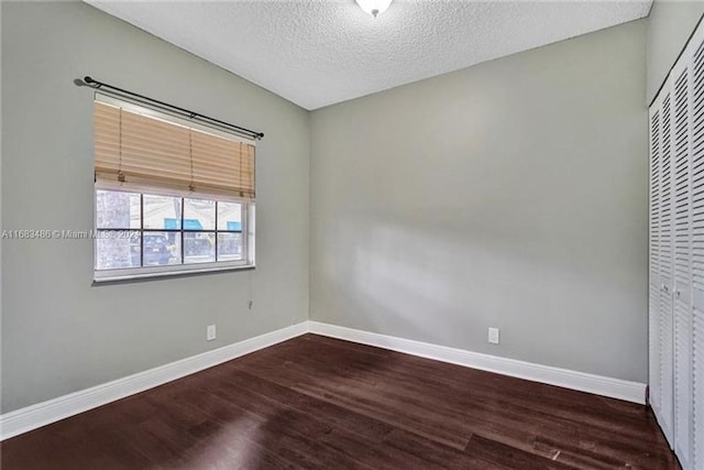 empty room with a textured ceiling and dark hardwood / wood-style floors