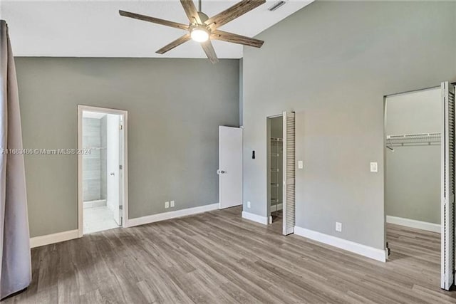 unfurnished bedroom featuring ensuite bathroom, ceiling fan, high vaulted ceiling, and light hardwood / wood-style flooring