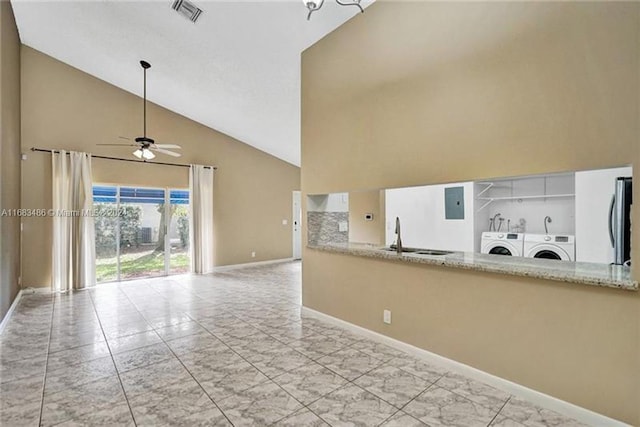 kitchen with stainless steel fridge, ceiling fan, sink, washer and dryer, and high vaulted ceiling