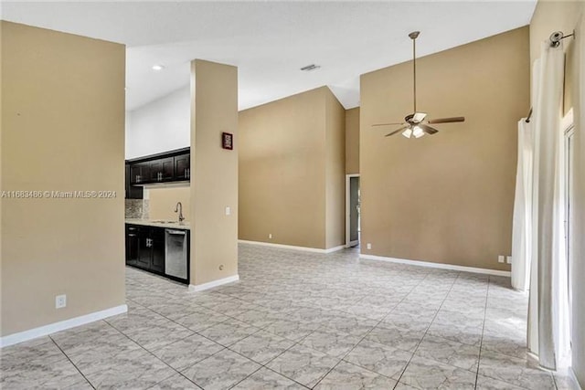 unfurnished living room with ceiling fan, sink, and a high ceiling