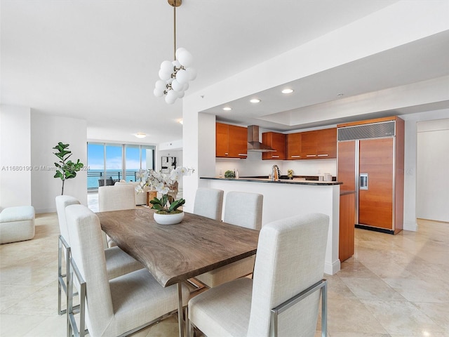 dining area with light tile patterned flooring, an inviting chandelier, sink, and a water view