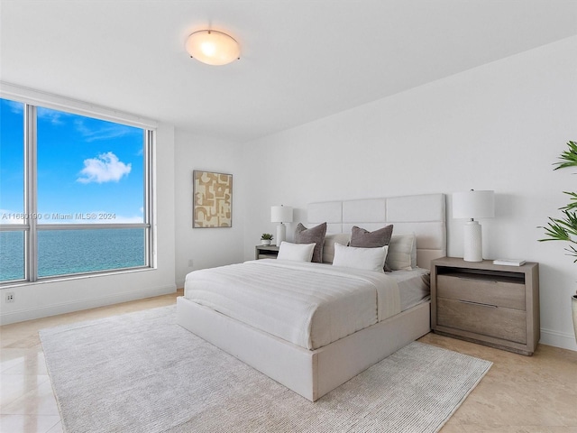 bedroom featuring light tile patterned flooring and a water view