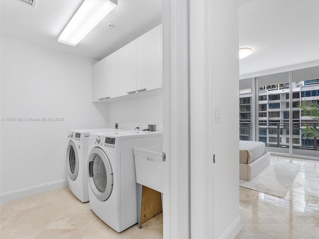 clothes washing area with independent washer and dryer and cabinets