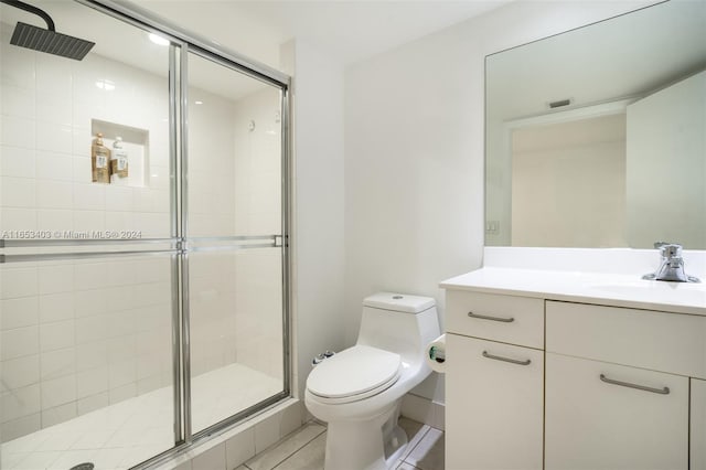 bathroom featuring tile patterned flooring, vanity, toilet, and a shower with shower door