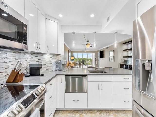 kitchen with hanging light fixtures, a breakfast bar, crown molding, white cabinetry, and appliances with stainless steel finishes