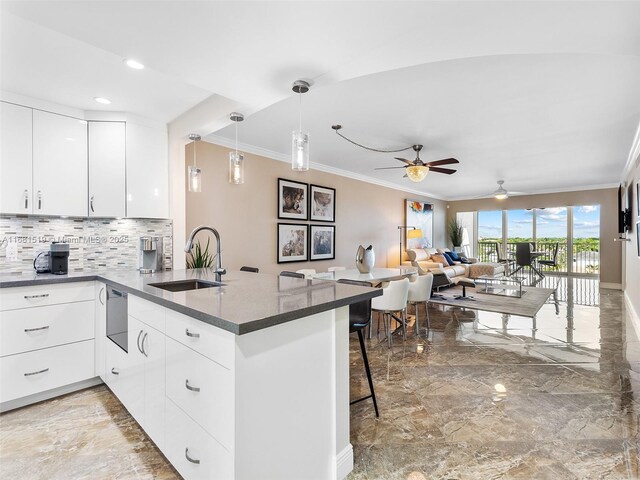 kitchen featuring light stone countertops, sink, stainless steel appliances, pendant lighting, and white cabinets