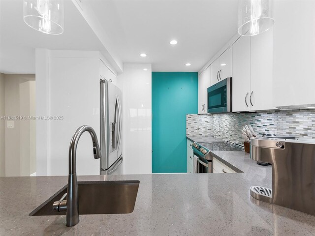 kitchen featuring white cabinetry, appliances with stainless steel finishes, sink, and hanging light fixtures