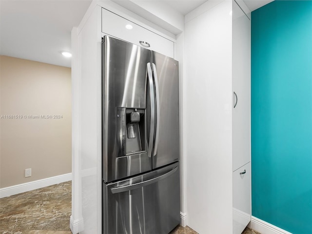 kitchen featuring stainless steel fridge and white cabinets