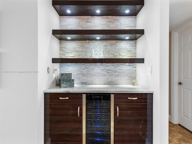 bar with dark brown cabinetry, wine cooler, and tasteful backsplash