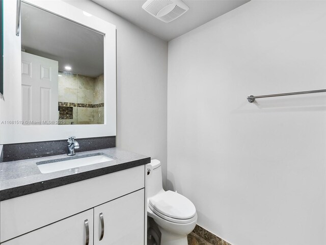 bathroom featuring vanity, toilet, and a tile shower