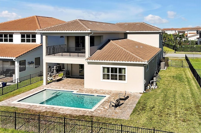 back of house featuring a balcony, a fenced in pool, a patio area, and a lawn