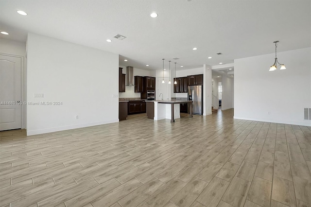 unfurnished living room featuring light hardwood / wood-style floors, a textured ceiling, sink, and a chandelier