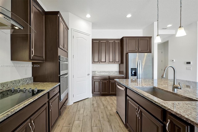 kitchen featuring decorative light fixtures, dark brown cabinetry, stainless steel appliances, and extractor fan