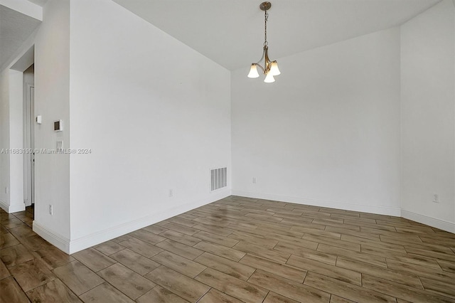 empty room with hardwood / wood-style flooring and an inviting chandelier