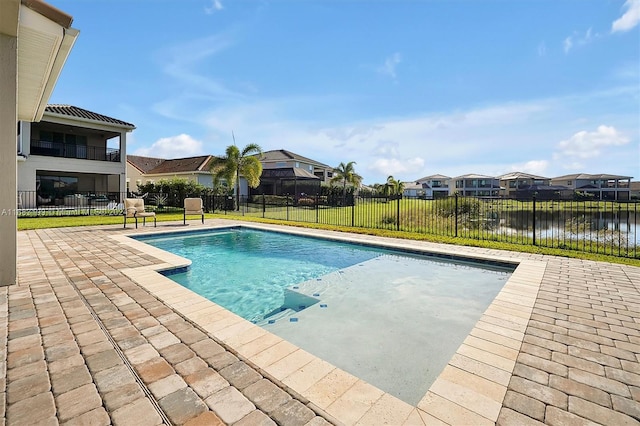 view of pool with a water view, a patio, and a lawn