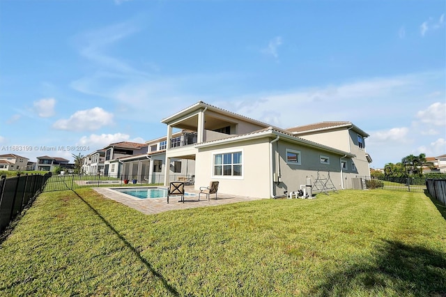 rear view of property with central AC unit, a balcony, a lawn, a patio, and a fenced in pool