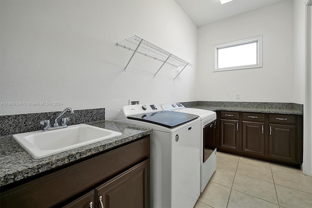 clothes washing area featuring light tile patterned floors, sink, separate washer and dryer, and cabinets