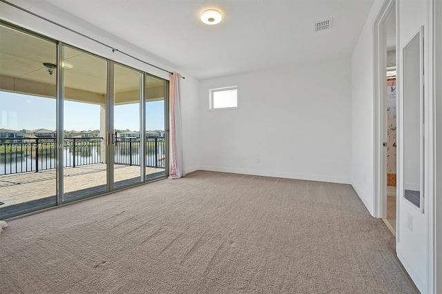 carpeted spare room featuring a water view