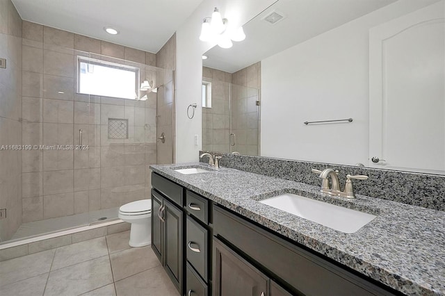 bathroom featuring a shower with door, vanity, toilet, and tile patterned floors