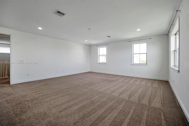 carpeted empty room with a textured ceiling