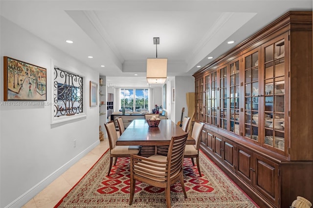 tiled dining room with crown molding and a tray ceiling