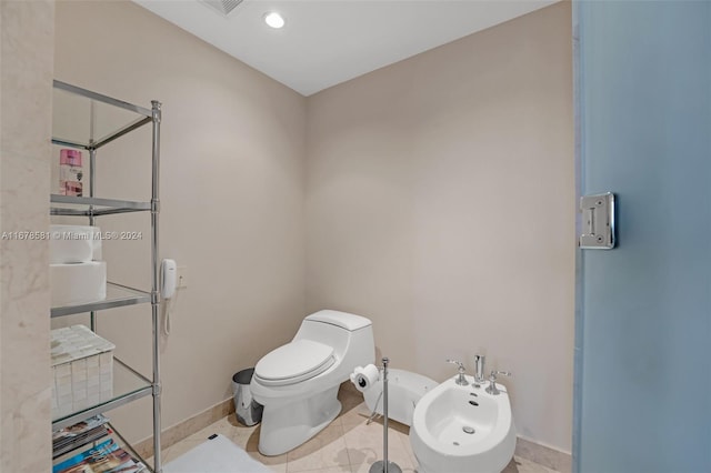 bathroom with a bidet, toilet, and tile patterned flooring