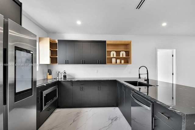 kitchen with dark stone counters, kitchen peninsula, sink, and stainless steel appliances