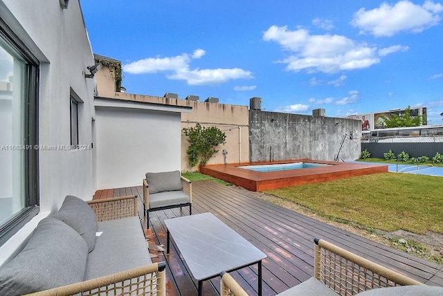 wooden deck featuring an outdoor hot tub and a lawn