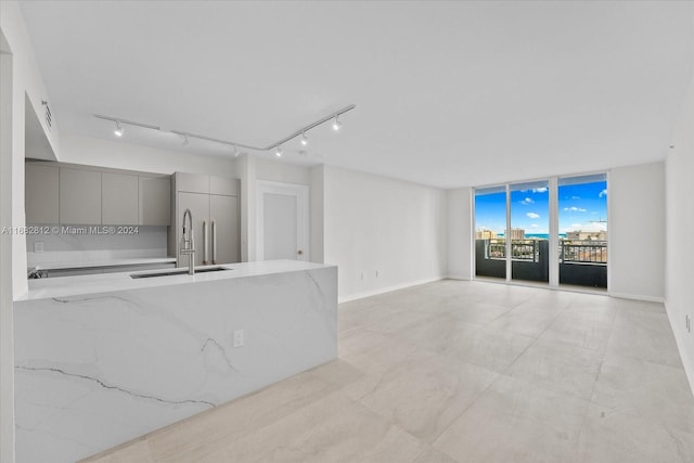 unfurnished living room with rail lighting, sink, and floor to ceiling windows