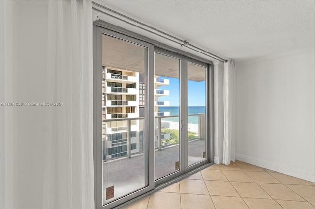 doorway with light tile patterned floors, a water view, baseboards, and a textured ceiling
