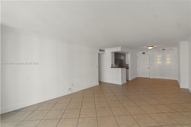unfurnished living room featuring light tile patterned floors, baseboards, a textured ceiling, and visible vents