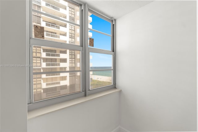 unfurnished room featuring a water view and baseboards