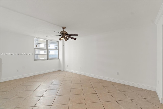 tiled empty room featuring ornamental molding and ceiling fan