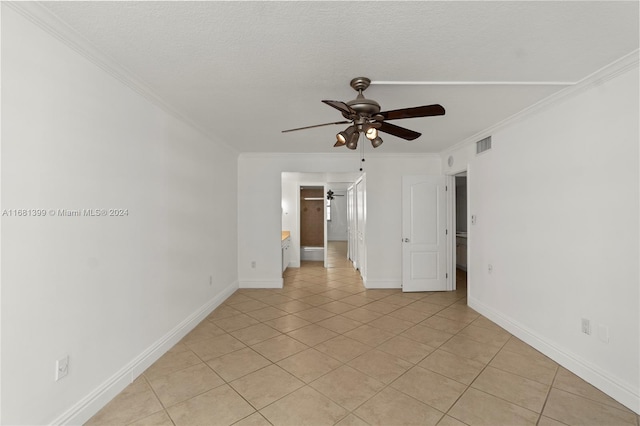 spare room with light tile patterned floors, ceiling fan, ornamental molding, and visible vents