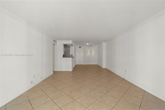 empty room with baseboards, ornamental molding, and light tile patterned flooring