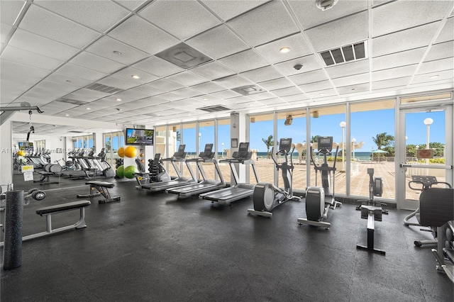 exercise room featuring floor to ceiling windows, a paneled ceiling, and visible vents