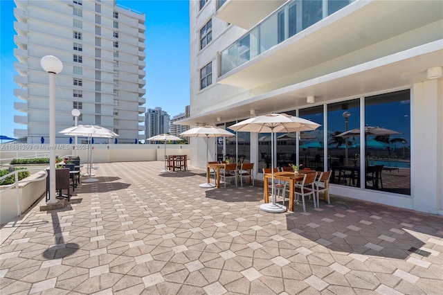 view of property's community featuring fence, outdoor dining area, and a patio area