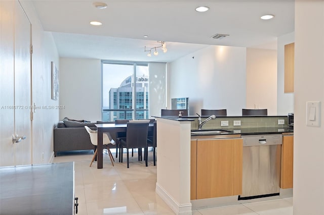 kitchen with stainless steel dishwasher, sink, decorative backsplash, and light tile patterned floors