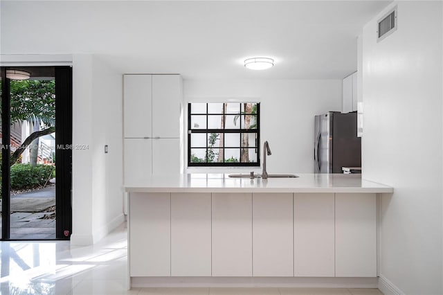 kitchen featuring sink, stainless steel fridge, kitchen peninsula, and a healthy amount of sunlight