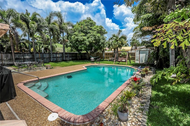 view of pool with a storage shed and a lawn