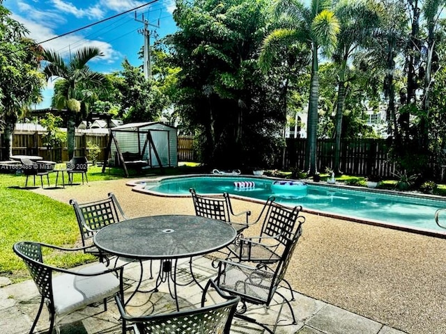 view of swimming pool featuring a storage shed, a lawn, and a patio area