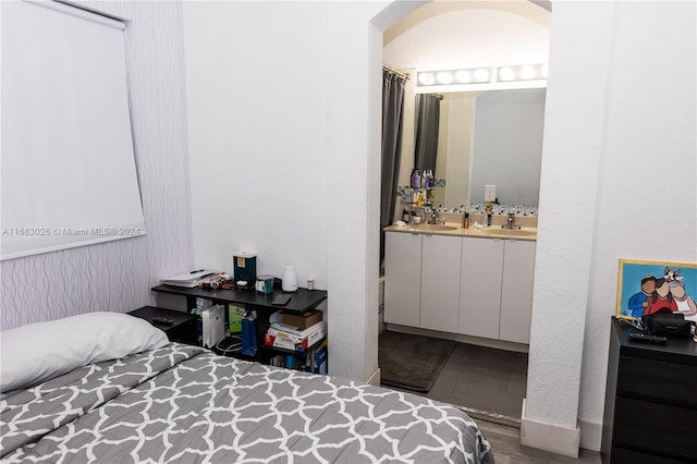 bedroom featuring dark wood-type flooring, ensuite bath, and sink