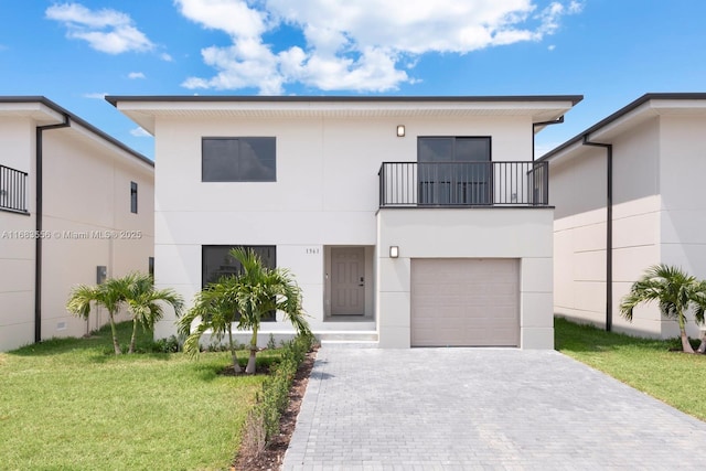 view of front of house featuring a front lawn, stucco siding, decorative driveway, a balcony, and an attached garage