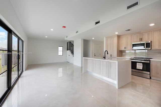 kitchen featuring visible vents, light brown cabinetry, a sink, stainless steel appliances, and light countertops