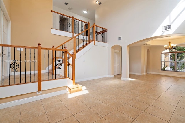 stairway with a high ceiling, an inviting chandelier, and tile patterned flooring