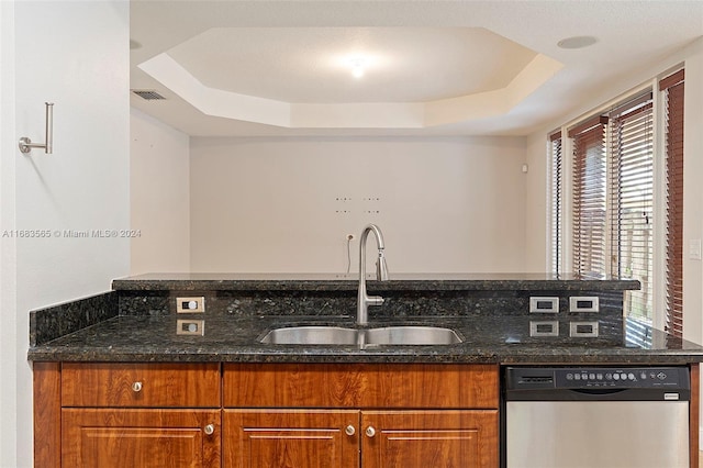 kitchen featuring sink, dishwasher, a tray ceiling, and dark stone counters